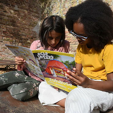 Zwei Kinder lesen gespannt eine Ausgabe des Magazins "echt jetzt?"