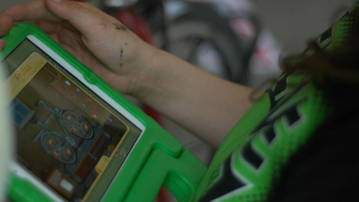 Ein Kind hat ein Tablet in der Hand auf dem die Forscherwelt-App der Stiftung zu sehen ist