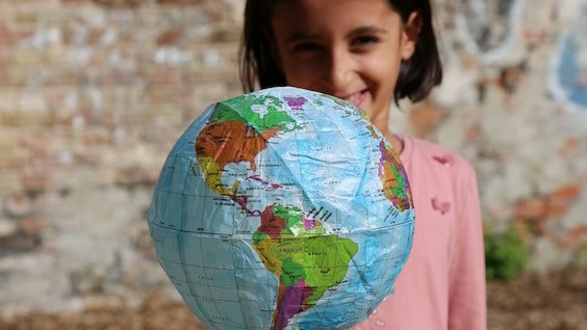 Ein Mädchen hält einen aufblasbaren Globus in die Kamera.