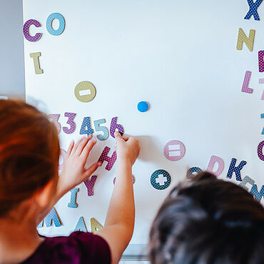 Kinder kleben Magnete an eine Tafel