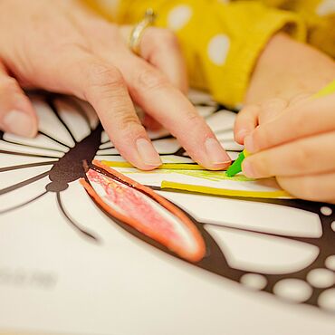 Kinderhand malt Schmetterlingvorlage auf Papier aus