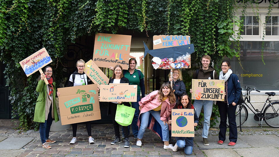 Mitarbeitende der Stiftungen halten Demo-Schilder für Klimaschutz