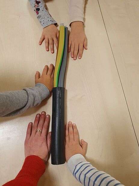 Kinderhände mit dickem Stromkabel