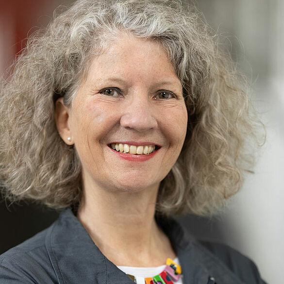 Porträt von C. Katharina Spieß, eine Frau mit lockigen blonden Haaren im grauen Blazer