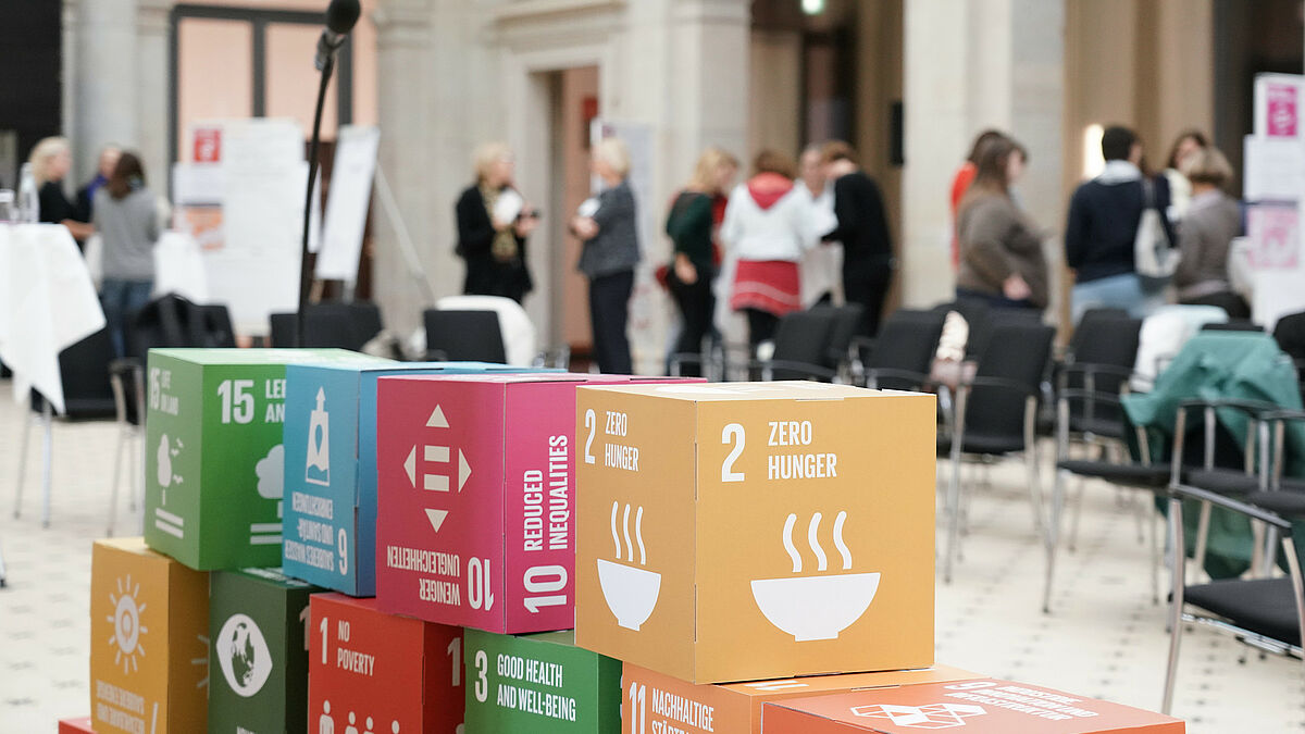 Bunte Würfel mit den internationalen Nachhaltigkeitszielen stehen gestapelt auf einer Veranstaltung
