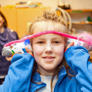 Ein Kind hält sich Gegenstände ans Ohr, um die akustische Wirkung zu testen.